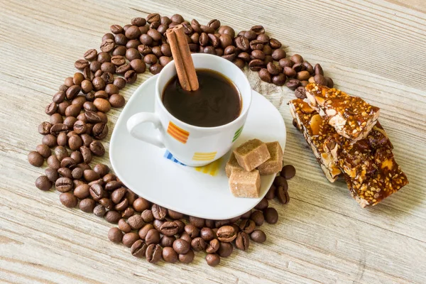 Kubek kawy z przyprawami, ziarna kawy, cynamon, i słodycze na rustykalne drewniane tło przypominające Internet e-maile symbol — Zdjęcie stockowe