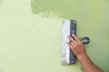 Müteahhit işçi el tek parmak olmadan alçı için spatula tutan ve yeşil boyalı ıslak beton uygulayarak. İşçi kavramının engeli.