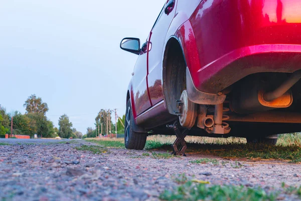 Concepto de servicio de neumáticos pinchados. Coche de pie en el lado de la carretera con una rueda quitada . — Foto de Stock