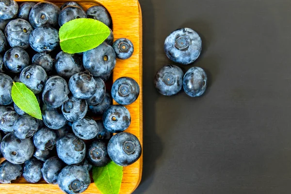 Blueberries with a leaf on a black stone background with copy space — Stock Photo, Image