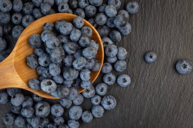 Taştan bir arka planda yaban mersini ve ahşap bir kaşık.