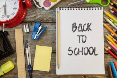 Okula dönüş konsepti kırtasiye malzemelerinin ortasında not defteri ve kalemle uydurma..