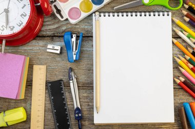 Okula dönüş konsepti kırtasiye malzemelerinin ortasında not defteri ve kalemle uydurma.