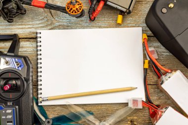 Hobi İHA yarışı konsepti. Drone, uzaktan kumanda, video alıcısı, şarj aleti ve eski ahşap arka planda durgun bir yaşam için 5 hücreli pervaneli kuadkopter pervaneleri. Metin için alanı kopyala