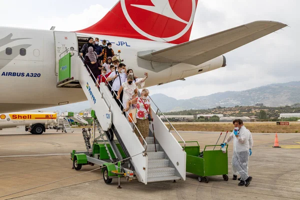 Gazipasha, Antalya, Türkiye - 09 Ağustos 2020: Türk Havayolları yolcu uçağı Gazipasha GZP Havaalanı 'na yolcu indiriyor. Yolcu koruyucu maskeler takıyor ve temizlik ekibi uçağı sterilize etmek için bekliyor.