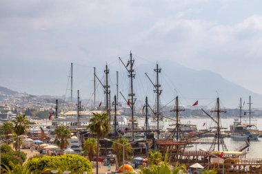 Alanya, Türkiye - 28 Ağustos 2020: Üzerinde bulutlarla kaplı dağlarla park etmiş turizm gemileriyle kıyı hattı. Antalia eğlence sezonu bu yıl