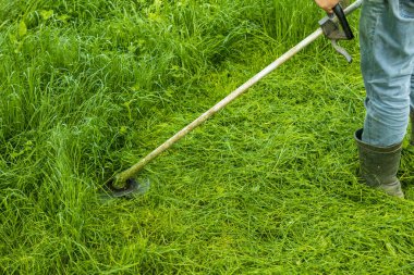 Çiftçi, çim biçme makinesinin yakın çekimini hareket ettirir ve bir çim biçer.