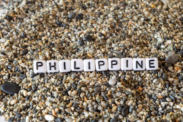 Philippine inscription text with name of the vacation destination city in a still life of the letters laid out on a shore sand stones