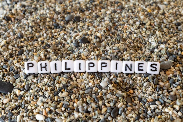 Philippines inscription text with name of the vacation destination city in a still life of the letters laid out on a shore sand stones