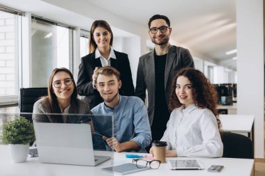 Ekip çalışması kavramı. Modern ofis yeni başlangıç projede çalışan ve kameraya bakarak genç yaratıcı iş arkadaşları.