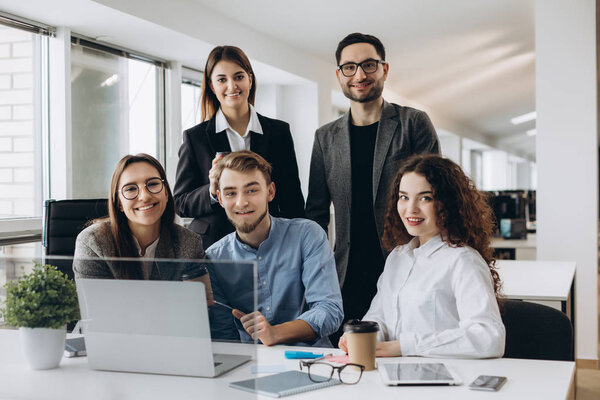 Teamwork concept.Young creative coworkers working with new startup project in modern office and looking at camera.