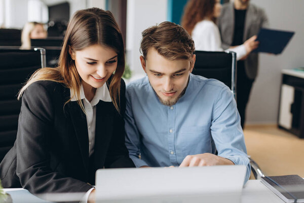 Coworkers looking at a computer and talking about work.