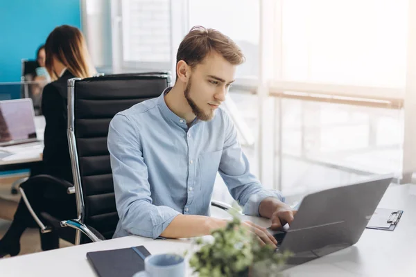 Portrait of young man sitting at his desk in the office — Stock Photo, Image