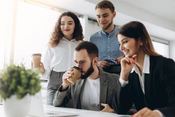 Concentración total en el trabajo. Grupo de jóvenes empresarios que trabajan y se comunican sentados en el escritorio de la oficina junto con colegas sentados en segundo plano — Foto de Stock