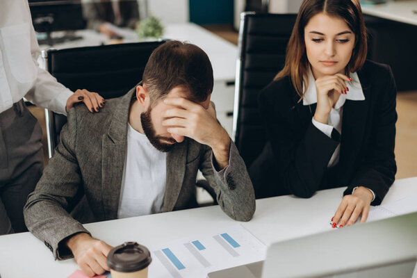 Sad man sitting at the desk in office looking at laptop screen having problem, bad news. Side view of stressed, businessman noticed the error, failed to work, failure in business concept