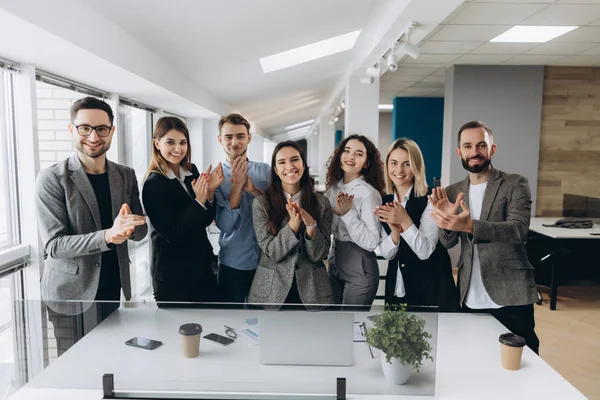 Beau boulot ! Une équipe d'affaires prospère applaudit leurs mains dans un poste de travail moderne, célébrant la performance du nouveau produit — Photo