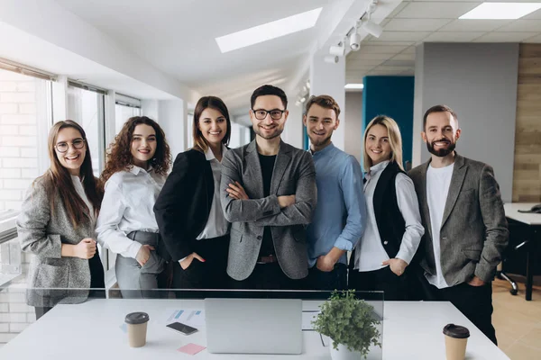 Bir satırda birlikte parlak bir modern ofis ayakta çeşitli kurumsal iş arkadaşları gülümseyen bir grup portresi