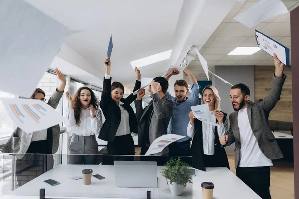Resmi office zaferini kutluyor mutlu iş takım. Başarılı iş takım kağıt parçaları modern ofiste atar..