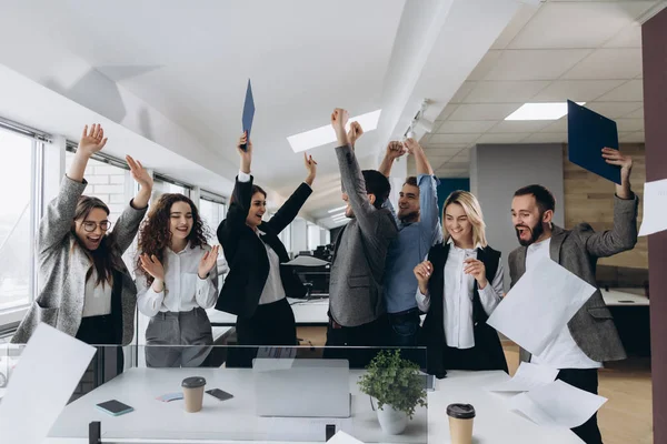 Image d'une équipe d'affaires heureuse célébrant la victoire au pouvoir. Une équipe d'affaires prospère jette des morceaux de papier dans un bureau moderne . — Photo