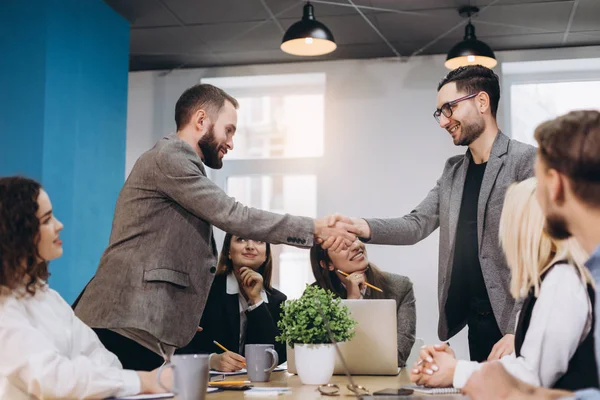 Jóvenes empresarios dando la mano en la oficina. Finalización de la reunión exitosa . — Foto de Stock