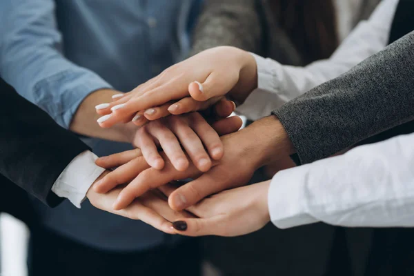 Vista de cerca de la parte superior de los jóvenes empresarios poniendo sus manos juntas. Un montón de manos. Unidad y concepto de trabajo en equipo. — Foto de Stock