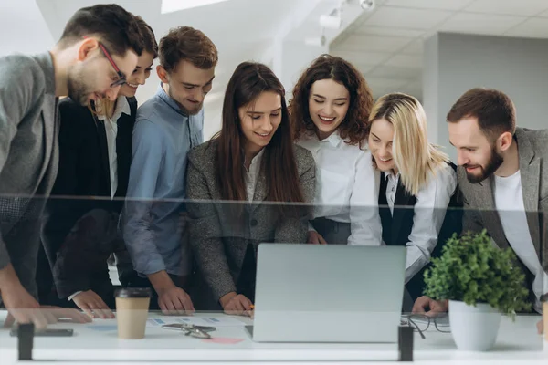 Trabajando juntos. Grupo de jóvenes modernos en ropa casual inteligente discutiendo negocios y sonriendo en la oficina creativa — Foto de Stock