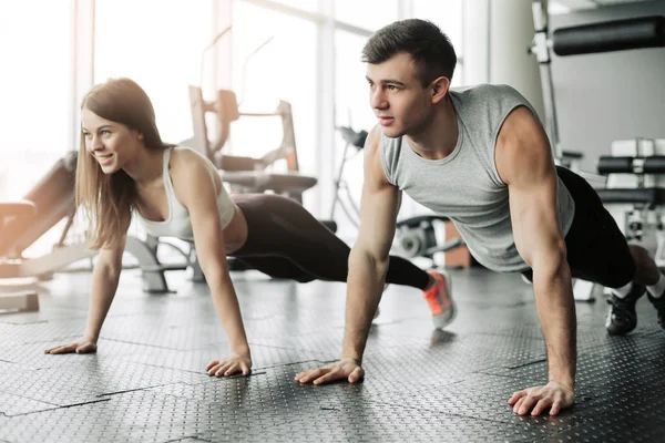Σπορ νεαρό ζευγάρι κάνει άσκηση σανίδα στο γυμναστήριο — Φωτογραφία Αρχείου
