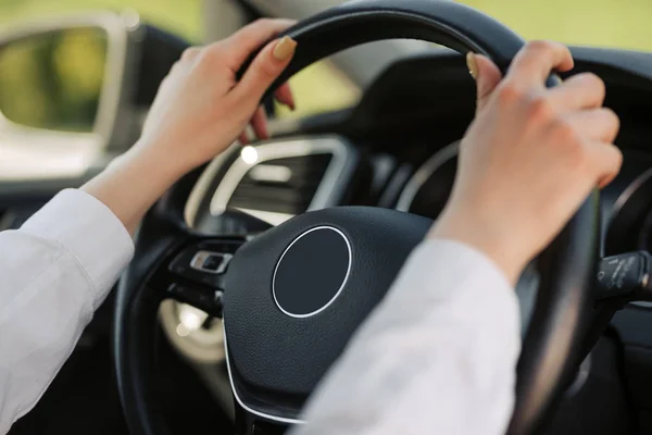 Kvinnans händer håller i svart ratt när du kör bil. — Stockfoto
