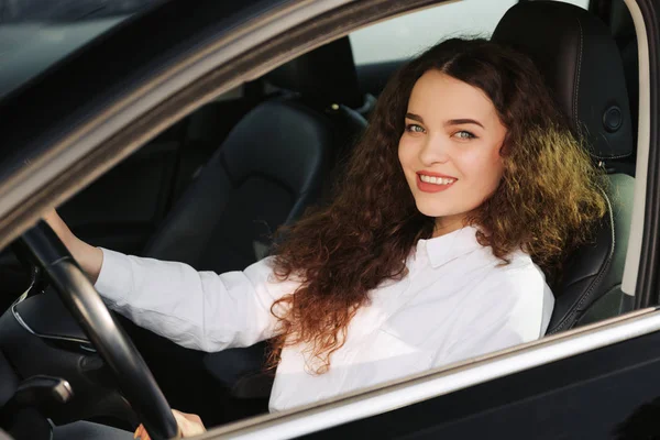 Primer plano retrato de mujer de aspecto agradable con alegre expresión positiva, estar satisfecho con el viaje inolvidable en coche, se sienta en el asiento del conductor, disfruta de la música. Personas, conducción, concepto de transporte — Foto de Stock