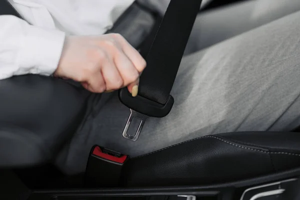 Kvinnors hand fäster bilens säkerhetsbälte. Stäng bilbältes bältet när du sitter inne i bilen innan du kör bil och gör en säker resa. Närbild skott av kvinnlig förare fäster säkerhetsbälte. — Stockfoto