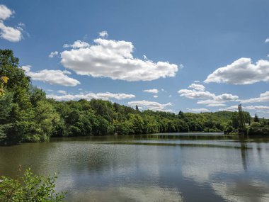 Durgun göl yüzeyinin panoramik görüntüsü Çek Cumhuriyeti 'ndeki Mnisek kapsülü brdy yakınlarındaki bulutlu gökyüzünü yansıtıyor.