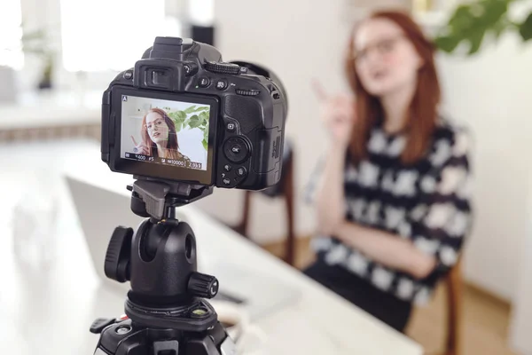 Young female blogger filming video on digital camera at home
