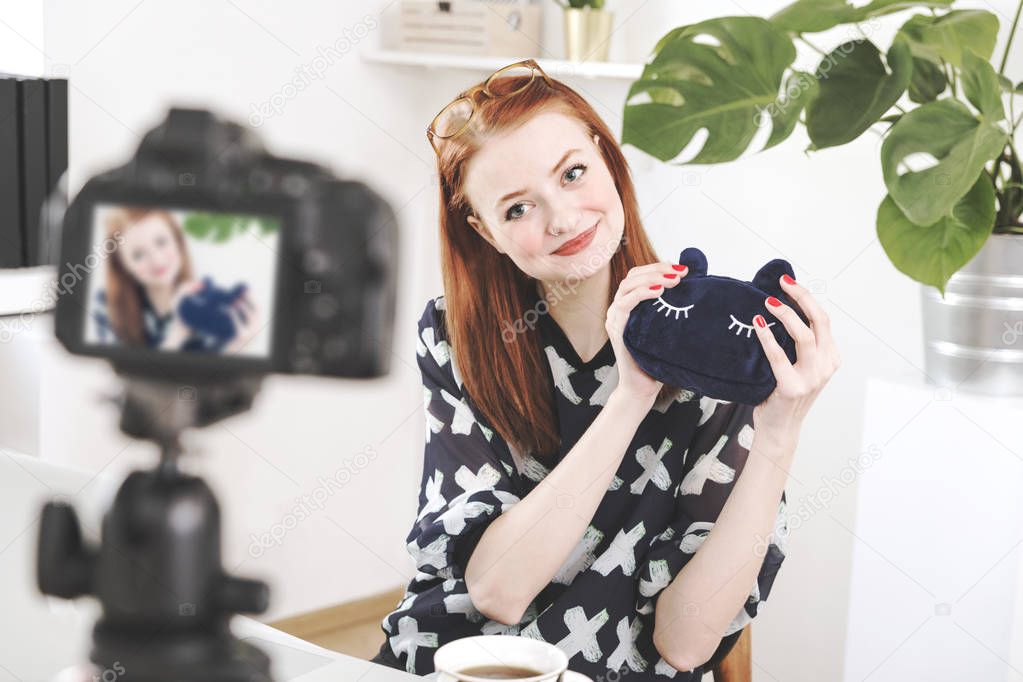 Young female blogger filming video on digital camera at home