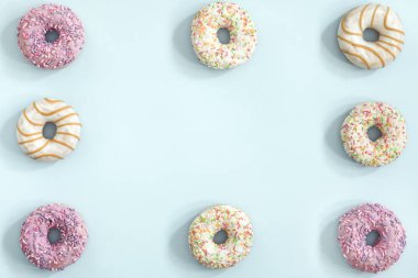 Pastel mavi zemin üzerine sırlı donuts topluluğu