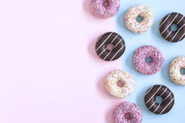 Pastel pembe ve mavi arka plan üzerinde sırlı donuts topluluğu