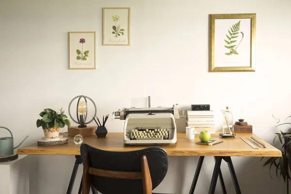ヴィンテージタイプライター 植物のポスターイラスト テーブルランプ 木製デスク オフィスアクセサリーを備えたスタイリッシュなホームオフィス — ストック写真