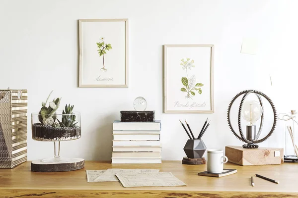 Vintage, creative home office interior with wooden desk, books, laptop, romantic illustrations of plants, table lamp and office accessories.