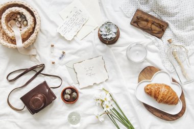 Şık düz kartları, gözlük, pastel pembe makaronlar, beyaz çarşaf arka plan üzerinde kadın aksesuarları ile yatakta çalışma alanı yatıyordu. Düz yatıyordu, üst görünüm blogger influencer ev ofis kavramı.