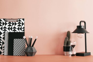 Kaktüsler, ofis aksesuarları, yapışkan notlar ve siyah lamba ile Kırmızı pastel masa. Kırmızı arka plan duvarlı yaratıcı çalışma alanı. Ev dekorasyonunun şık ve modern kompozisyonu.
