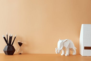 Kopya alanı, fil figürü ile yaratıcı turuncu pastel masa. Boş pastel duvar. Minimalist kavram. Şablon. Ev dekorasyonunun şık ve modern kompozisyonu.