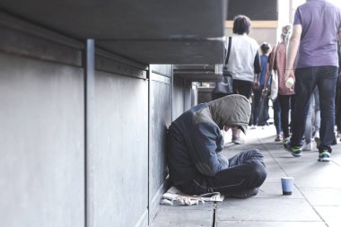 Dinleyici notları için Kupası ile kaldırımda oturan evsiz adam