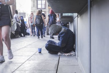 Dinleyici notları için Kupası ile kaldırımda oturan evsiz adam