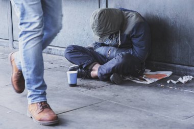 Dinleyici notları için Kupası ile kaldırımda oturan evsiz adam