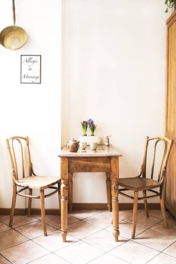 Basit sandalye ve bitki süslemeleri ile beyaz duvara karşı küçük bir masa ile mutfak alanı Vintage iç tasarım. Mutfak alanı minimalist kavramı.