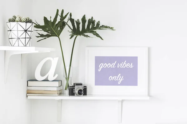 Bright white interior corner with shelves and inspirational phrase in frame on wall