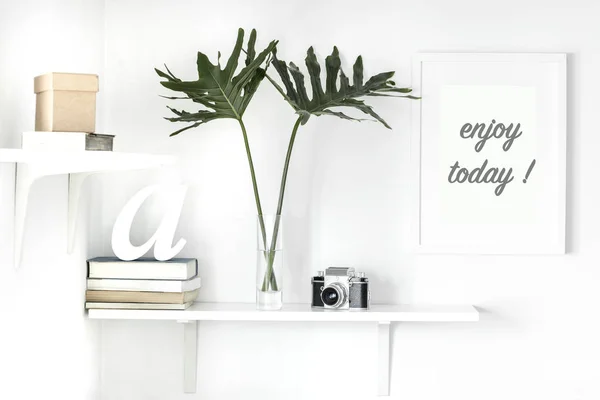 Bright white interior corner with shelves and inspirational phrase in frame on wall