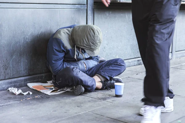 无家可归的人坐在人行道上拿着杯子施舍 — 图库照片