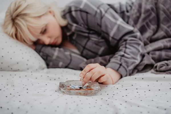 Junge Frau Liegt Mit Aschenbecher Voller Zigarettenkippen Bett — Stockfoto