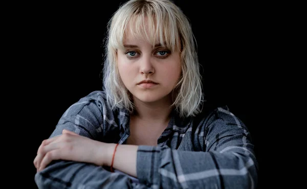 Portrait of sad depressed young woman on black background