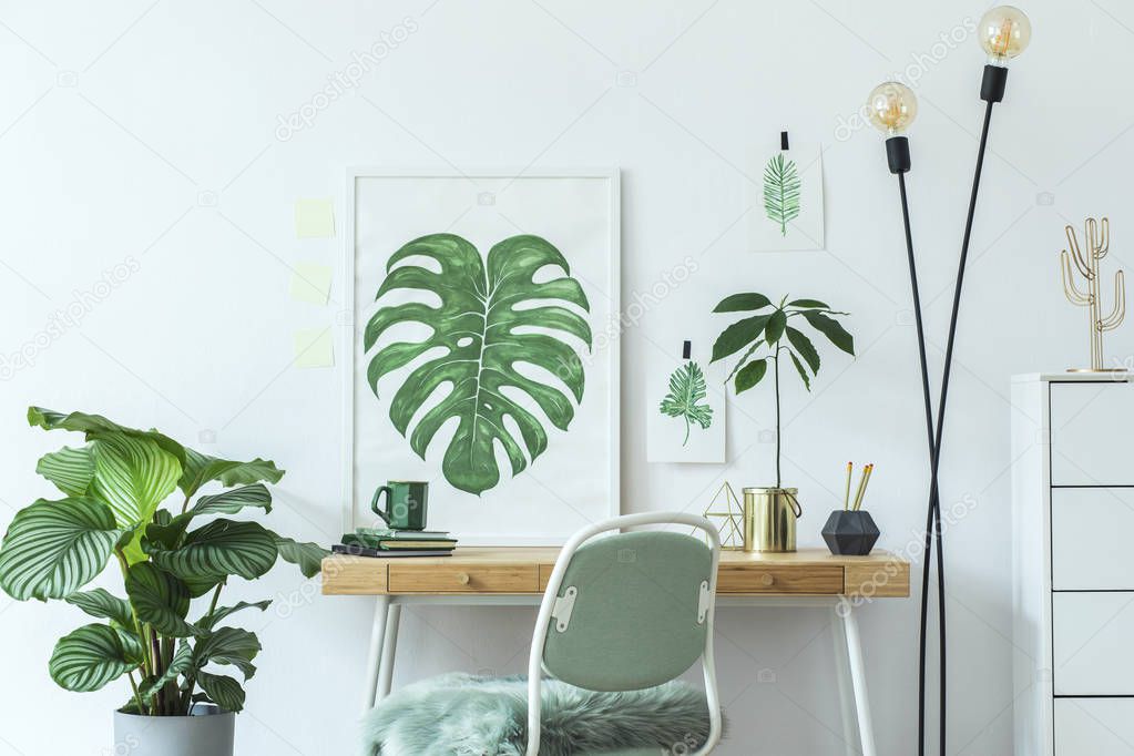 Stylish and modern scandinavian interior of home office desk with mock up poster frames, a lot of plants , office accessories and lamp. Modern composition of homeoffice desk.